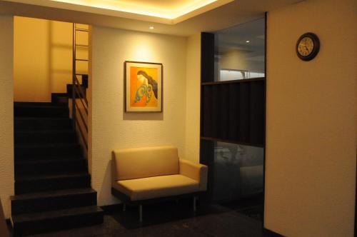a waiting room with a chair and a staircase at Ixora Suites in Bengaluru