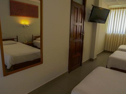 a hotel room with two beds and a mirror at Grand Hotel Mercedes in Pucallpa