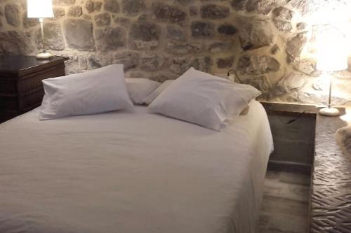 a bed with white pillows and a stone wall at Apartamento en Cantabria, Treceño in Treceño