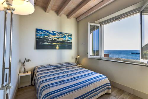 a bedroom with a bed and a large window at Il Quartiere apt Montecristo in Pomonte