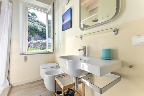a bathroom with a sink and a toilet and a mirror at Il Quartiere apt Montecristo in Pomonte