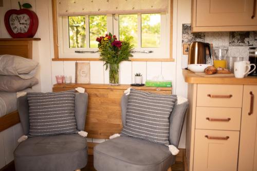 two chairs in a kitchen with two windows at Harrys Hideout - Shepherd's Huts at Harrys Cottages in Pen y Clawdd