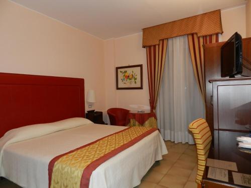 a hotel room with a bed and a flat screen tv at Hotel Il Mulino in Capo dʼOrlando