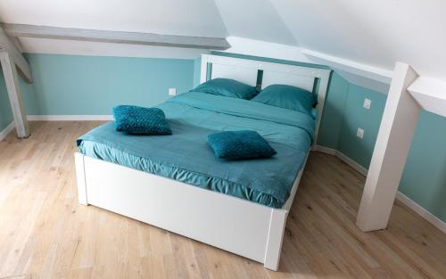 a white bed with blue pillows in a bedroom at EASYHOME DUNKERQUE in Dunkerque
