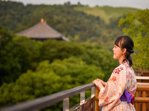 a woman in a kimono standing on a fence at Hotel New Wakasa in Nara