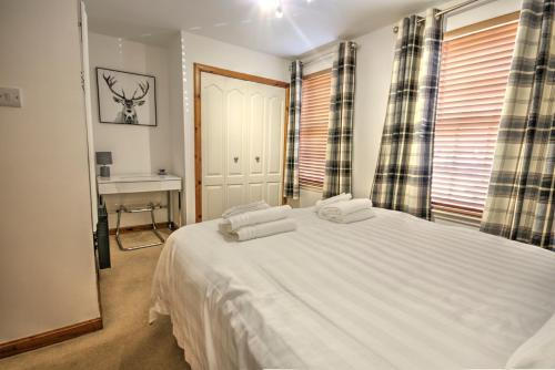 a bedroom with a large white bed with two pillows at 5 Argyle Place in Dornoch