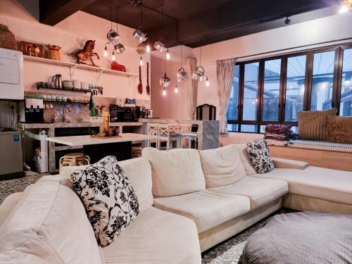 uma sala de estar com um sofá branco e uma cozinha em Clocktower Homestay 2 to 8 pax at Brinchang, Cameron Highlands em Cameron Highlands