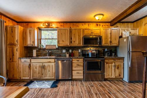 a kitchen with wooden cabinets and stainless steel appliances at Fun cabin with hot tub, pool table & fire pit - BIG BLUE in Bryson City