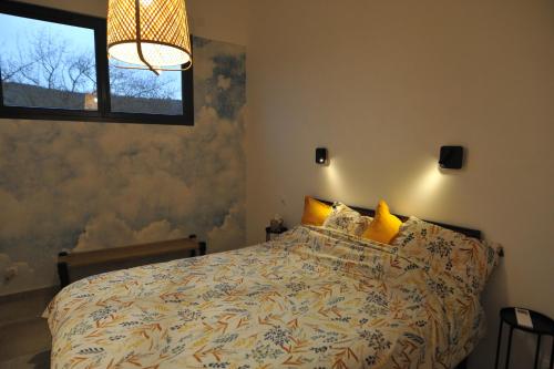 une chambre avec un lit avec des oreillers jaunes et une fenêtre dans l'établissement L'Embellie, maisonnette tout confort en pleine nature, à Suze