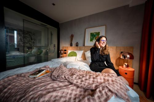 a woman sitting on top of a bed at KONCEPT HOTEL International in Cologne