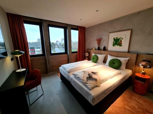 a bedroom with a bed and a desk and windows at KONCEPT HOTEL International in Cologne