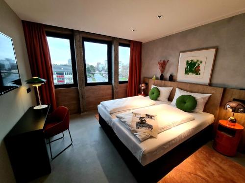 a bedroom with a bed and a desk and windows at KONCEPT HOTEL International in Cologne