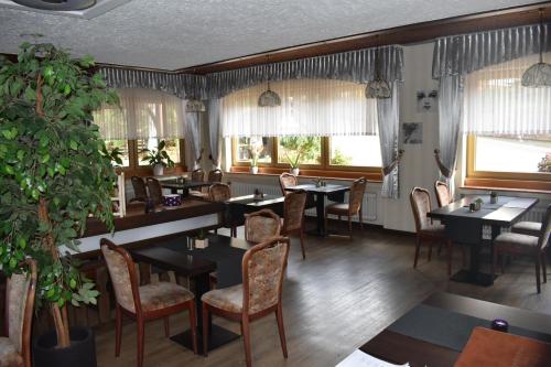 uma sala de jantar com mesas, cadeiras e janelas em Hotel-Restaurant Theis-Muehle em Biersdorf