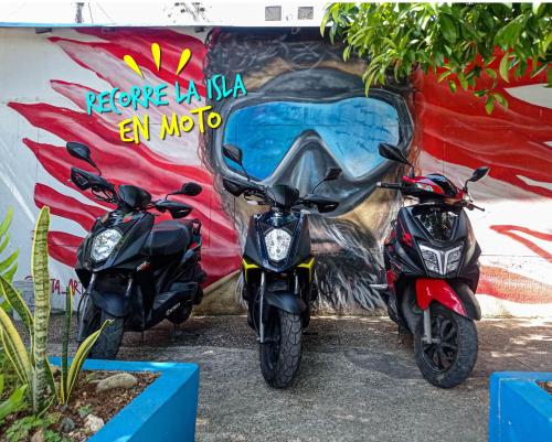 deux motos garées devant un mur avec une fresque murale dans l'établissement Posada Cultural Bahia Sonora, à San Andrés