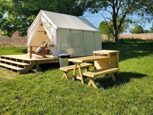 a tent with a picnic table and benches in the grass at Tentrr Signature Site - Sunflower Ridge at The Stickley Farm in Bluff City