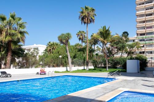 une piscine avec des palmiers et un bâtiment dans l'établissement Casa Sami, à Playa de las Americas