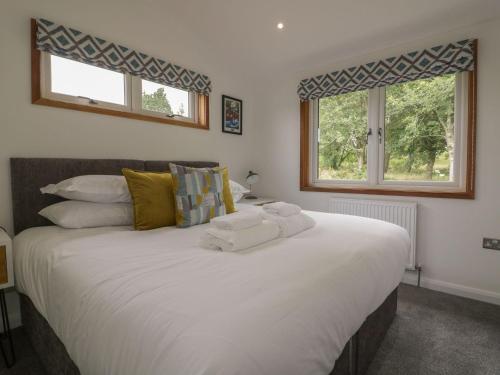 um quarto com uma grande cama branca e 2 janelas em 18 Meadow Retreat em Liskeard