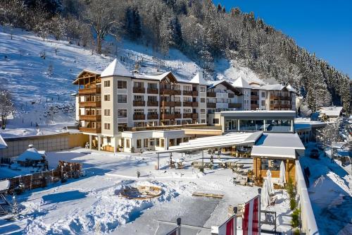 a hotel in the snow in front of a mountain at Superior Sport und Familienresort Alpenblick in Zell am See
