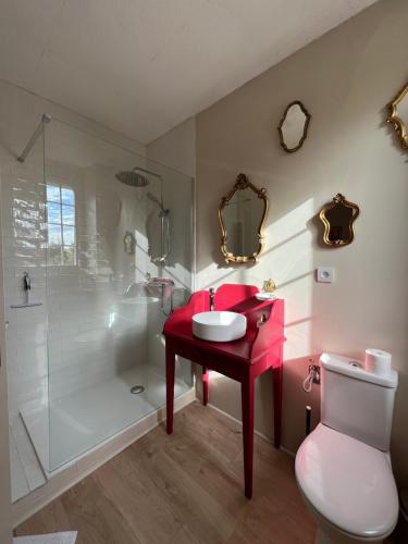 La salle de bains est pourvue d'un lavabo rouge et d'une douche. dans l'établissement L'ESCALE Chambres et table d'hôtes, à Verdun-sur-le-Doubs