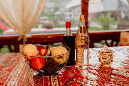 un bol de fruta y una botella de vino en una mesa en Casa Pintea de Sub Coastă en Breb