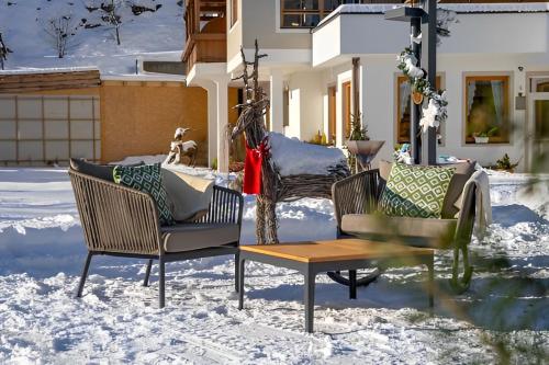 two chairs and a table in the snow at Superior Sport und Familienresort Alpenblick in Zell am See
