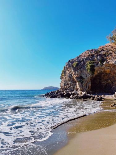 a beach with the ocean and a rocky cliff at Paradise on Kantouni Beach-20m from Boutique Hotel in Kalymnos
