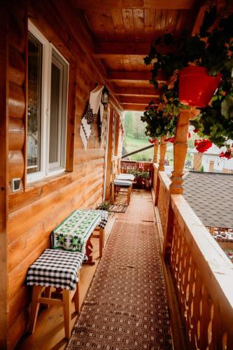 a porch of a wooden cabin with benches and windows at Casa Pintea de Sub Coastă in Breb
