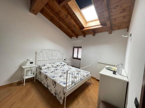 ein Schlafzimmer mit einem weißen Bett und einer Holzdecke in der Unterkunft Riso e Latte Casa Vacanze in Pisogne