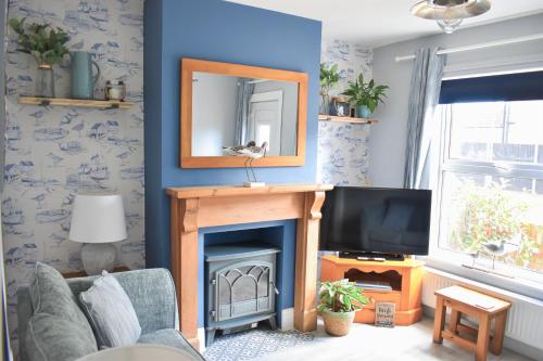 a living room with a fireplace and a mirror at Curlew Cottage - Suffolk Coastal Escapes in Pakefield