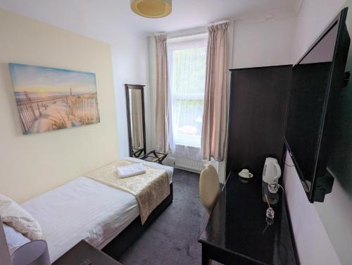 a bedroom with a bed and a desk and a window at Cecil Court Hotel in Bournemouth