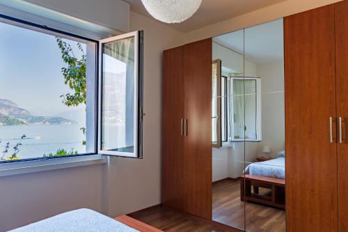 - une chambre avec une grande fenêtre, un lit et un miroir dans l'établissement Appartamento Sosta sul Lago, à Lezzeno