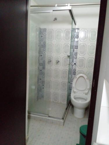 a bathroom with a toilet with a glass shower stall at montecarlos hotel in Ibagué