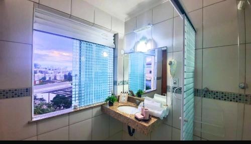 uma casa de banho com um lavatório, um espelho e uma janela em Flat bela vista master em Macaé