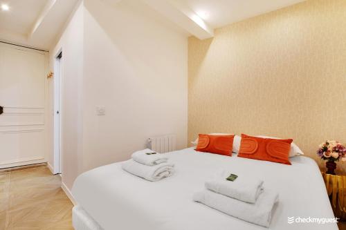 białe łóżko z pomarańczowymi poduszkami i ręcznikami w obiekcie Cosy apartment - 1BR-4P - Sentier w Paryżu