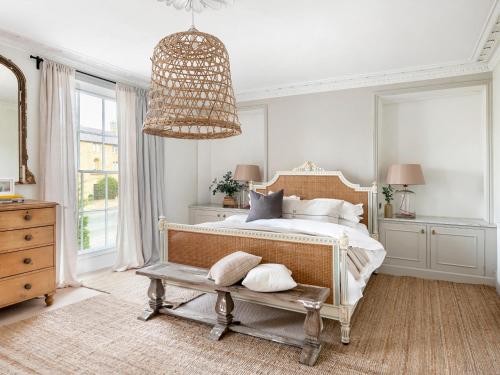1 dormitorio con cama y lámpara de araña en Cotswold House en Moreton in Marsh