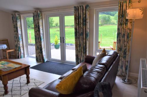 uma sala de estar com um sofá de couro e portas de vidro deslizantes em Alderneuk Lodge em Dumfries