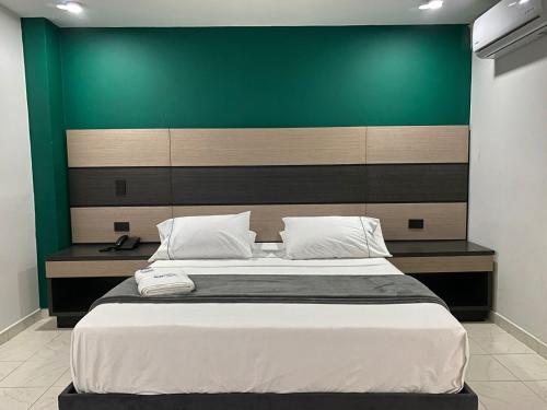 1 dormitorio con 1 cama grande y pared verde en Hotel Plaza Real Ocaña en Ocaña
