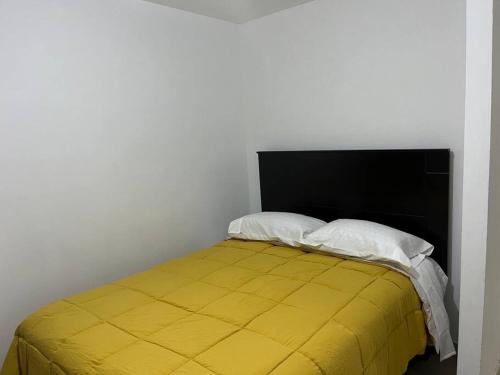 a bedroom with a yellow bed with two pillows at Departamento en Ica in Ica