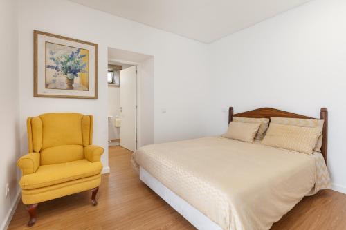 ein Schlafzimmer mit einem Bett und einem gelben Stuhl in der Unterkunft Casa dos Arcos in Caminha