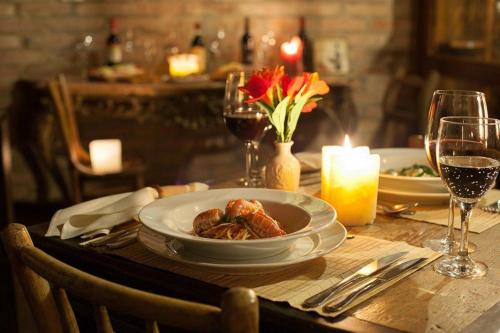 a table with a plate of food and glasses of wine at Confraria Colonial Hotel Boutique in Mairinque
