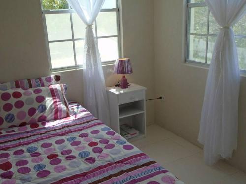 1 dormitorio con 1 cama y 1 mesa con lámpara en Simply Beautiful Two Storey home/apt awaits you, en Saint James