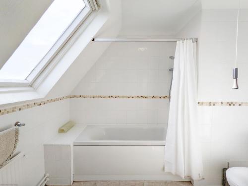 a bathroom with a bath tub and a window at 11 Shorecroft, Aldwick in Bognor Regis