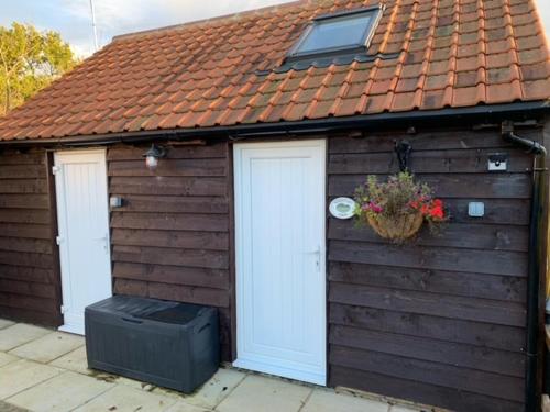 a brown shed with two doors and a flower pot at Whistley View in Brackley