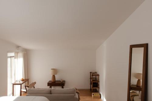 a white room with a couch and a mirror at A Padaria Farmhouse in Cinfães