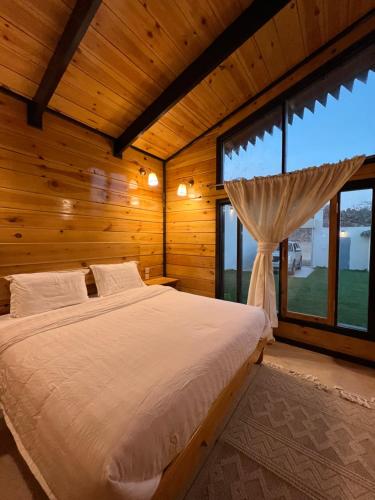 a bedroom with a bed and a large window at أكواخ ريف الطائف in As Sayl aş Şaghīr