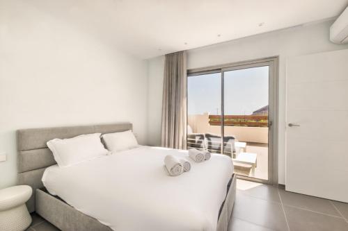 a bedroom with a white bed and a balcony at Jardines - Acoran 3-2 PENTHOUSE NATURAL RESERVE VIEW & JACUZZI in Palm-mar