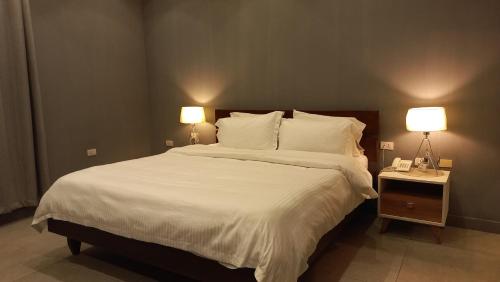a bedroom with a large bed with white sheets and two lamps at Tropicana Beach & Resort in Elwa
