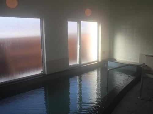a room with a pool of water with windows at Hotel Nakanoshima in Sobetsu