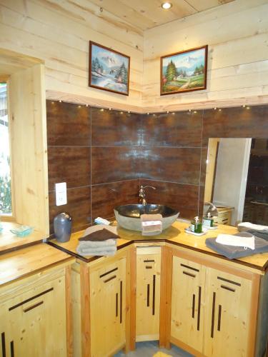 a bathroom with a sink and a wooden wall at L'Eterlou Chambres d'Hote in Albertville
