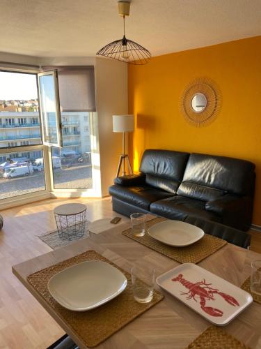 un salon avec un canapé en cuir noir et une table dans l'établissement Les Rameaux, superbe appartement vue mer, Wimereux, à Wimereux